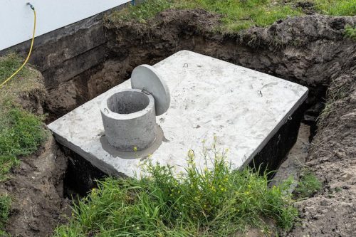 Concrete septic tank with a capacity of 10 cubic meters placed in the garden by the house, visible water below.